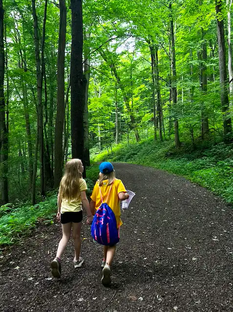 two girls walking on a forest trail