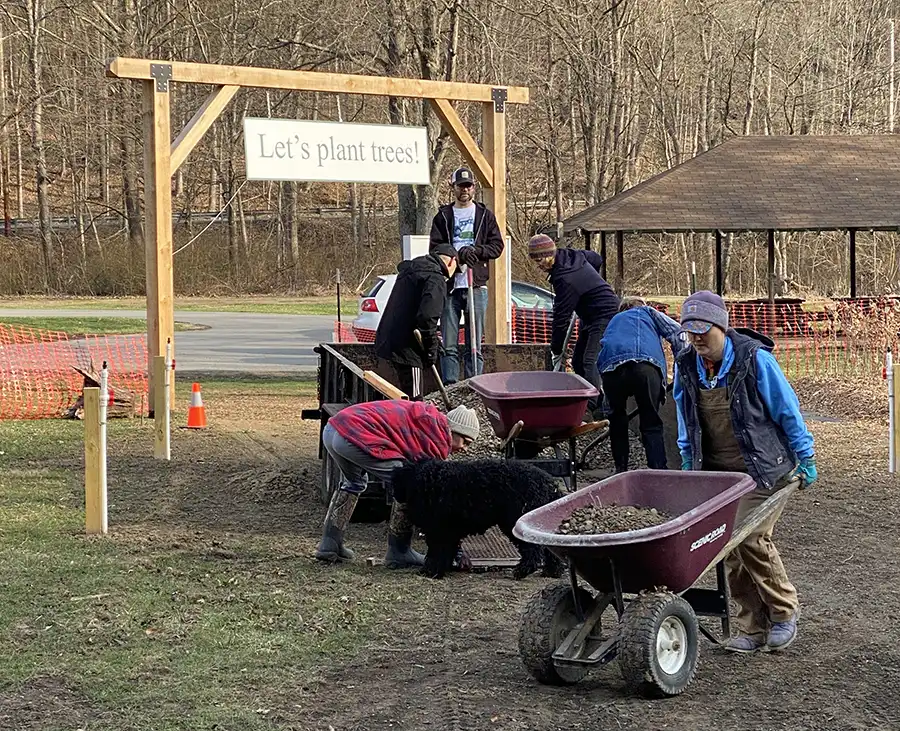 People pulling wheel barrels to help plant trees